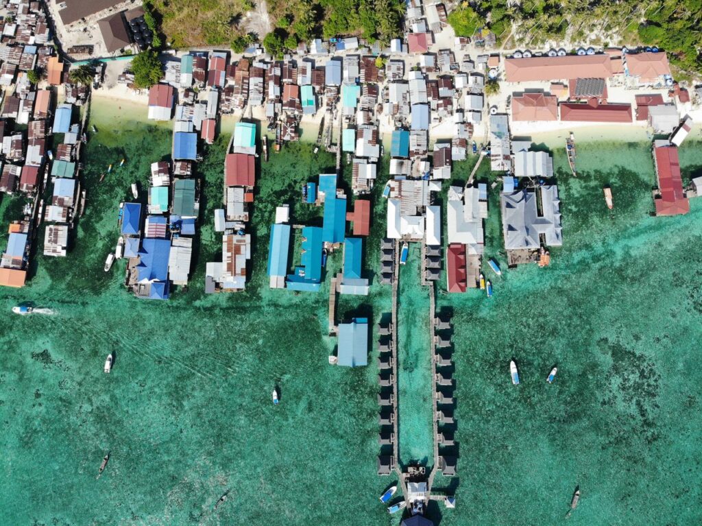 Drone view of island with various typical houses located near calm sea in tropical country on summer day in coastal area