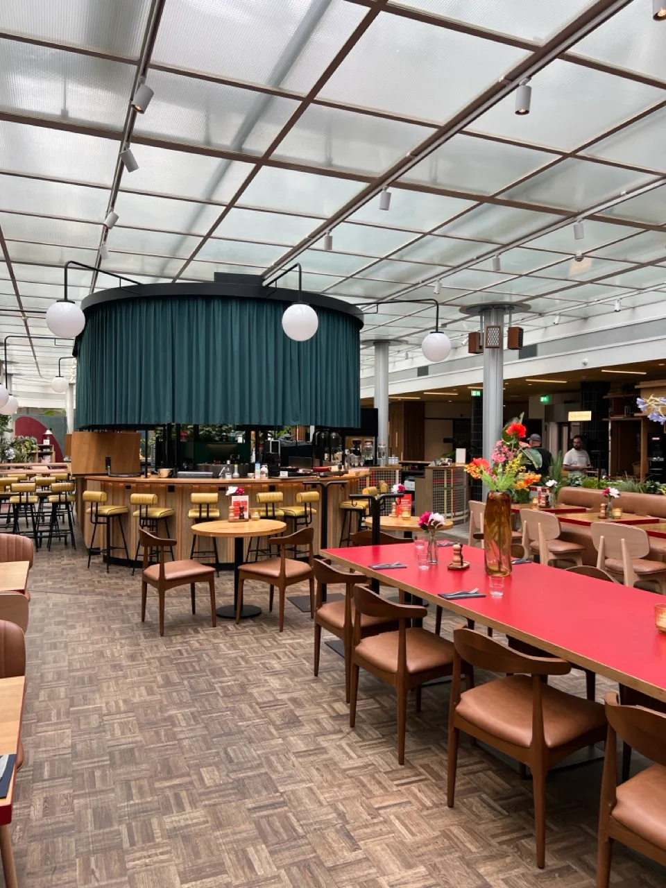 Frühstücksbereich unseres Hotels in Rotterdam mit Glasdach und roten Tischen