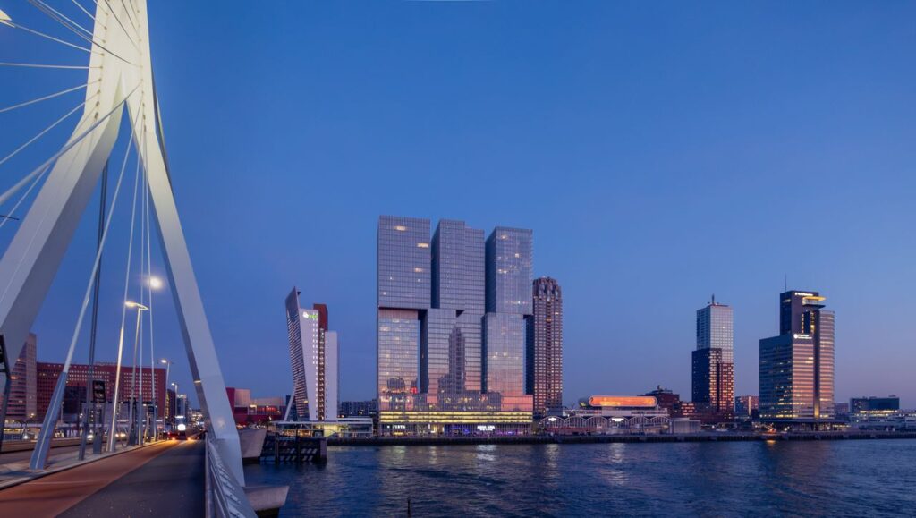 Stunning dusk view of Erasmus Bridge and Rotterdam skyline with modern architecture reflecting in the water.
