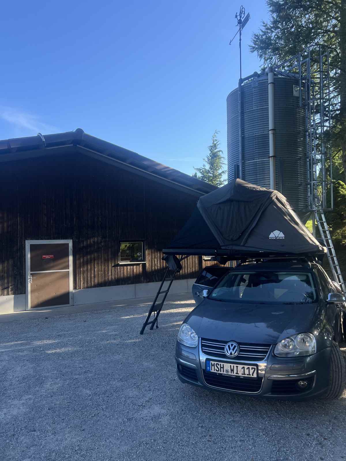 Dachzelt auf dem Auto vor einer Weingut-Scheune mit Silo in der Schweiz
