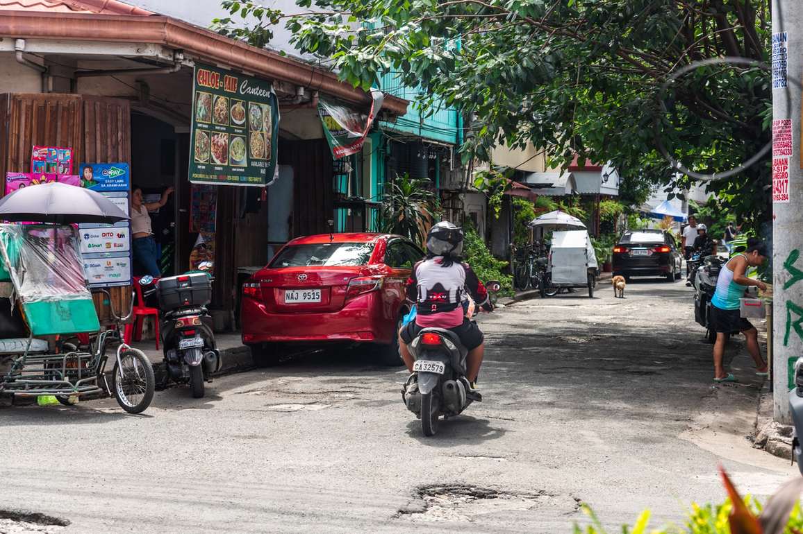 Seitenstraße in Manila mit kleinen Läden und Seitenwagen-Tricycle