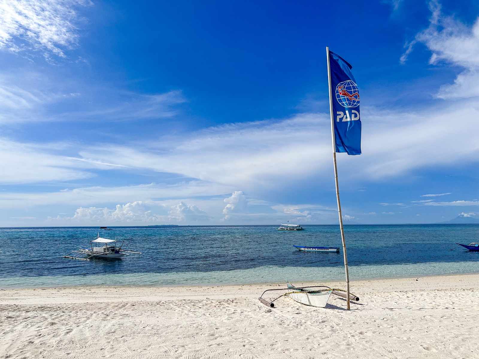 Weißer Strand auf Malapascua mit Bangka-Booten im blauen Meer
