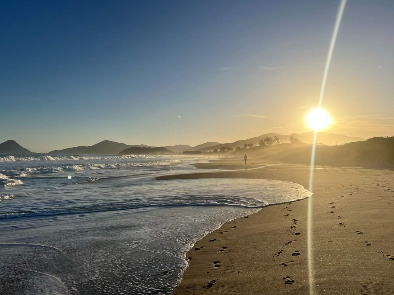 Weiter Strand mit Wellen im Abendlicht in Florianópolis, Brasilien